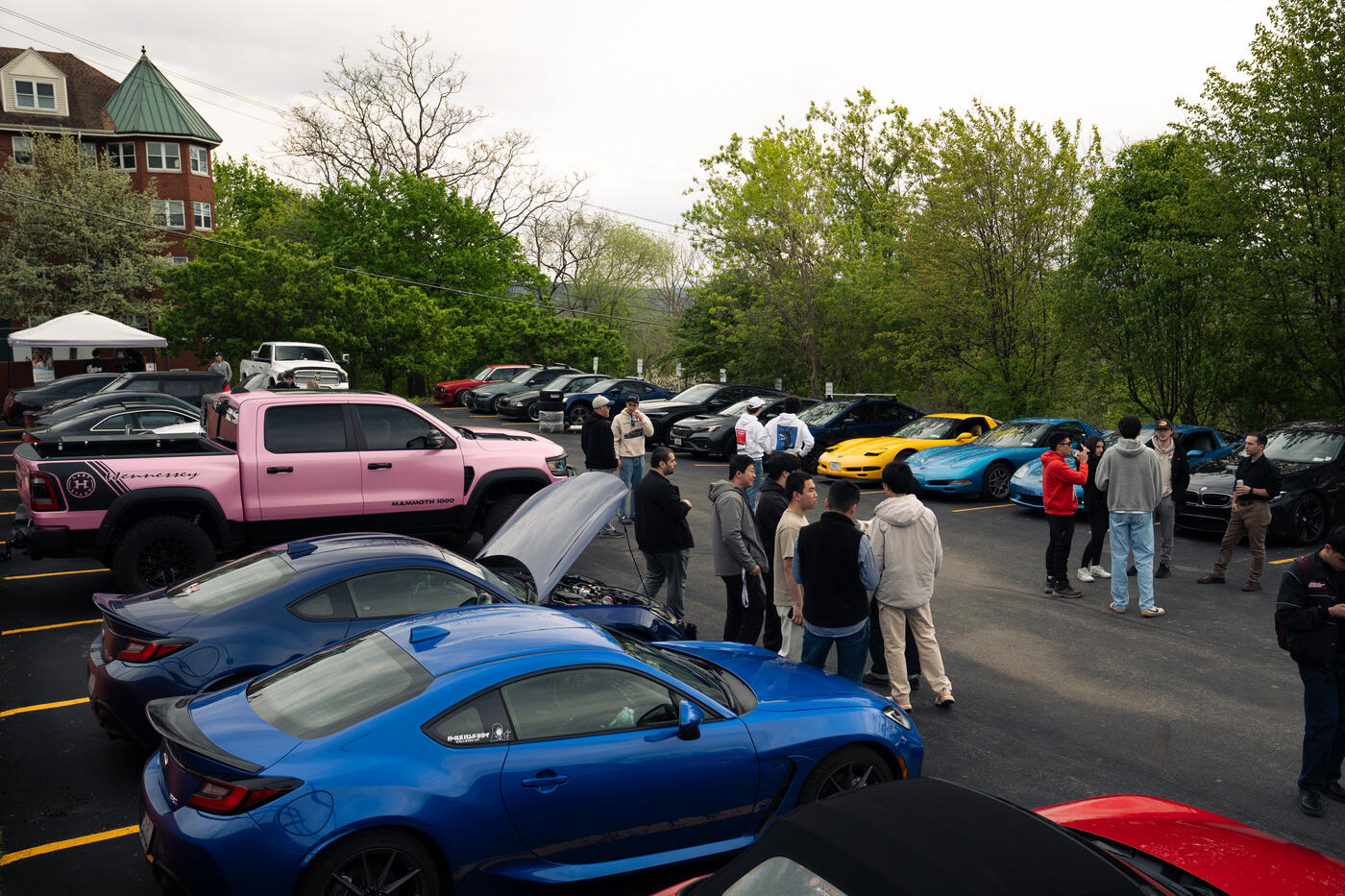 Students gathered around parked cars at a club meet